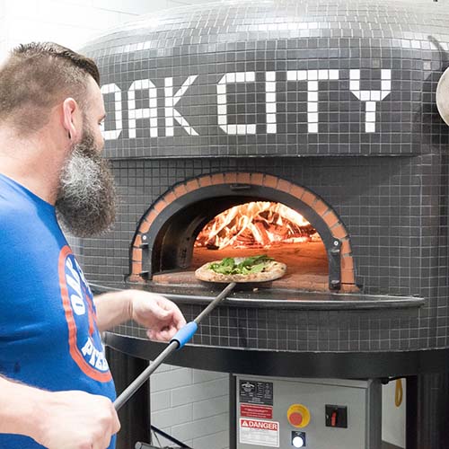 Matt Placing Pizza in Deck Oven at Oak City Pizza